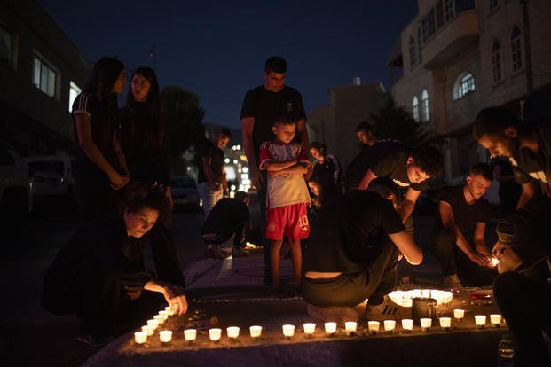 People light candles in memory of the children and teens killed in a rocket strike at a soccer field