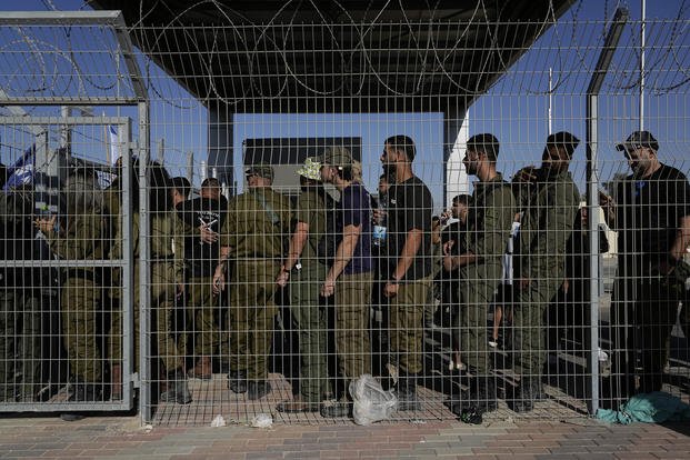 Israeli soldiers gather at the gate to the Sde Teiman military base