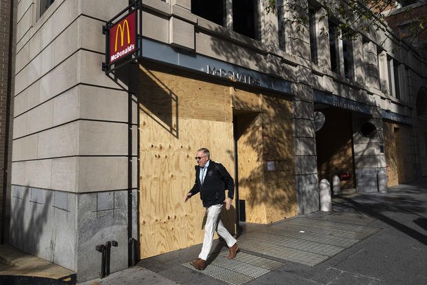 Pedestrian walks past boarded up stores near the White House in Washington