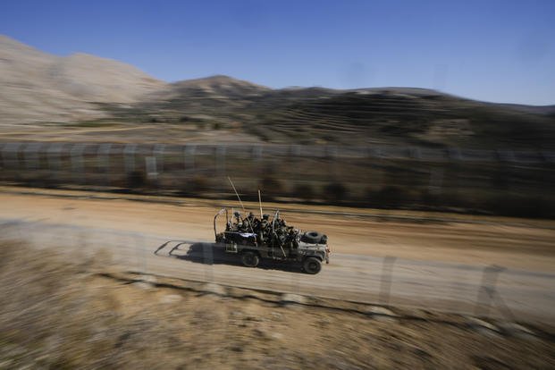 Israeli soldiers stand on an armored vehicle in the Golan Heights