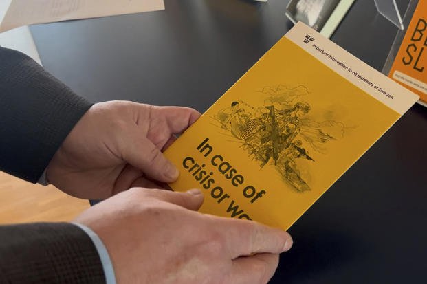 Swedish Civil Contingencies Agency expert holds a crisis preparedness brochure.