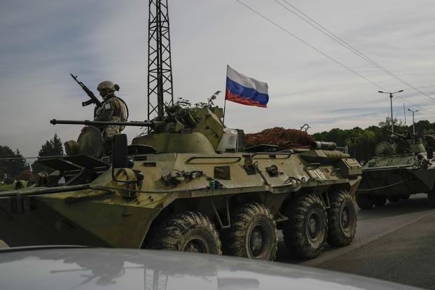 Russian army armored vehicles drive near the Hmeimim Air Base in Syria