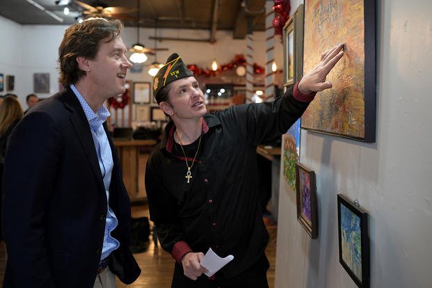 Veteran Brain Asbeck, right, show his artwork to Denver Mayor Mike Johnston at VFW Post 1 in Denver on Thursday, Dec. 19, 2024. Asbeck had been homeless for 4 years. 