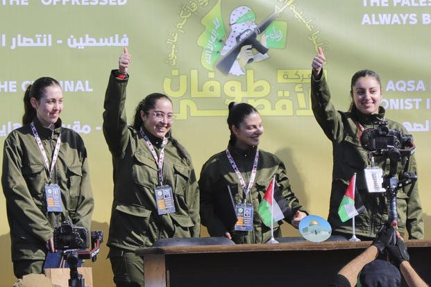 Israeli female soldier hostages wave to the crowd. 