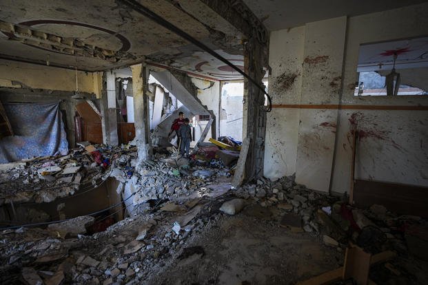 Palestinian kids look at a damaged residential building following an overnight Israeli strike