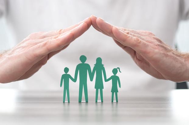 A man's hands form a roof over people-shaped green paper cutouts.