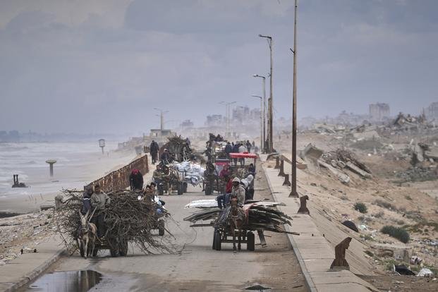 Displaced Palestinians carrying their belongings as they move between southern and northern Gaza.