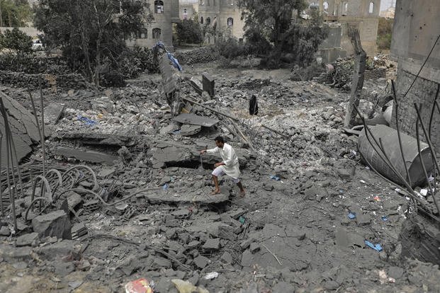 A Yemeni walks over the debris of a destroyed building following U.S. airstrikes
