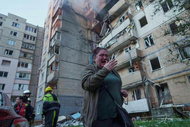 A woman reacts in front of a building heavily damaged by a Russian strike in Kyiv, Ukraine.