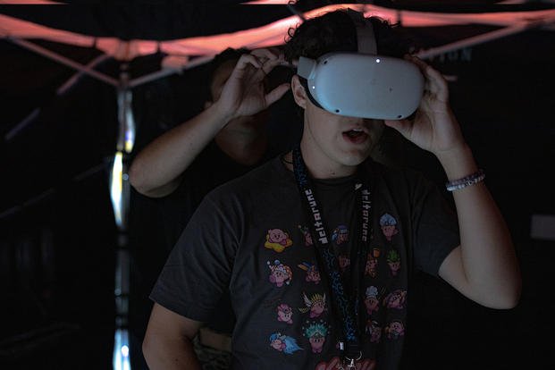 U.S. Marine Corps Sgt. Brandon Tubens adjusts a virtual reality headset on an event attendee during GalaxyCon in New Orleans.