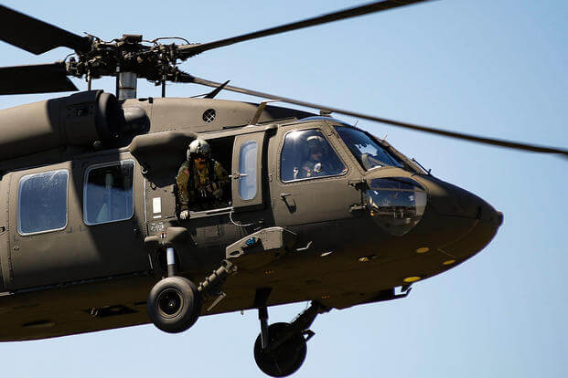 U.S. Army National Guard Staff Sgt. Gabe Cherian, a crew chief, looks out the door of a UH-60 Black Hawk helicopter to ensure clearance to land at the Ike Skelton Training Site in Jefferson City, Missouri.