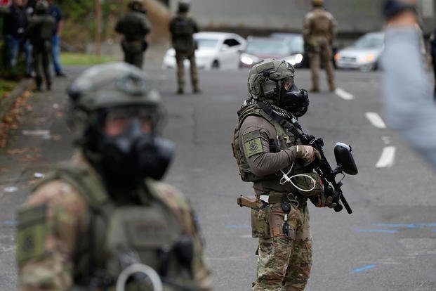 Immigration and Customs Enforcement agents stand outside an ICE facility during a protest in Portland, Ore. 