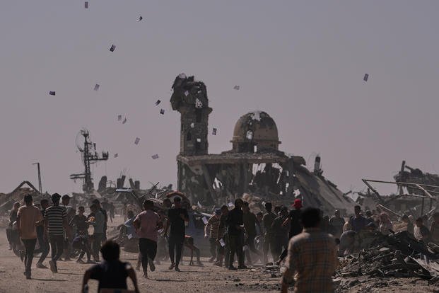 Palestinians collect leaflets dropped by an Israeli drone, warning people to stay away from the so-called yellow line in Khan Younis, in the southern Gaza Strip.