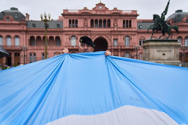 A retired military officer holds an Argentine flag.