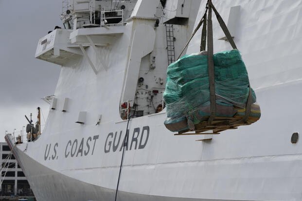 A palette loaded with bundles of seized cocaine and marijuana is lowered down by a crane, as the U.S. Coast Guard unloads more than one billion dollars worth of seized drugs from the Coast Guard Cutter James at Port Everglades, Thursday, Feb. 17, 2022, in Fort Lauderdale, Fla. (AP Photo/Rebecca Blackwell)