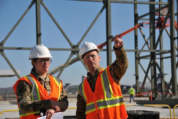 Air Force members in hard hats tour a construction site.