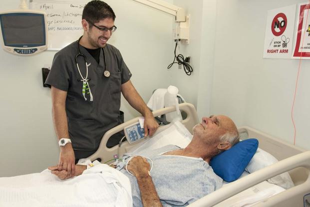 Jonathan Serna, a registered nurse at the William Beaumont Army Medical Center, checks on Henrie Schneider during Schneider's stay at WBAMC's Surgical Ward, April 11. (Marcy Snchez/ William Beaumont Army Medical Center)