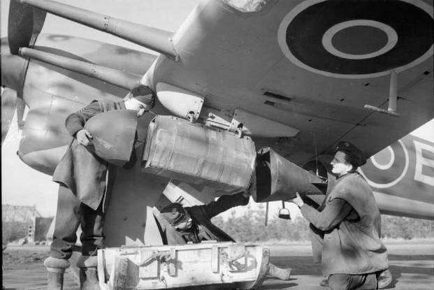 Royal Air Force- 2nd Tactical Air Force, 1943-1945. Armourers attach the nose and tail units onto a cluster projectile containing 26 x 20-lb anti-personnel bombs, fitted under the wing of a Hawker Typhoon Mark IB of No. 439 Squadron RCAF.