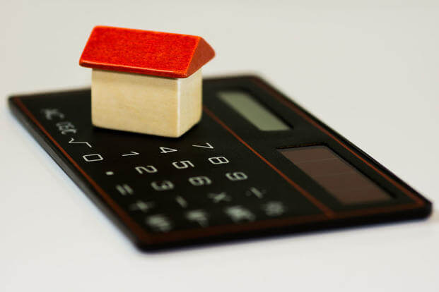 Small wooden house sitting on top of a calculator