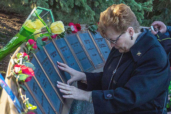 Linda DeFrancesco, mother of Senior Airman Lawrence DeFrancesco, places her hands on a plaque with her son’s name on it during a quiet moment before a ceremony at the Yukla 27 memorial. (U.S. Air Force/Justin Connaher)