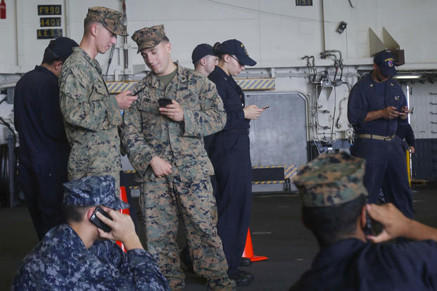 Marines and Sailors with the 15th Marine Expeditionary Unit and Sailors with America Amphibious Ready Group received an opportunity to talk to family using their mobile phones aboard USS America, Aug. 24, 2017. (U.S. Marine Corps photo/Jacob Pruitt)