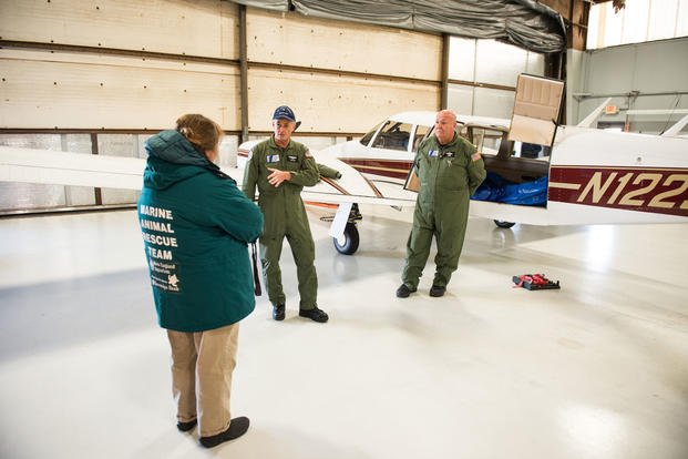 Two Coast Guard Auxiliary pilots talk with a member of the Marine Animal Rescue Team from the New England Aquarium about the logistics of flying rescued sea turtles, Thursday, Jan. 7, 2016. (U.S. Coast Guard photo by Petty Officer 3rd Class Ross Ruddell)