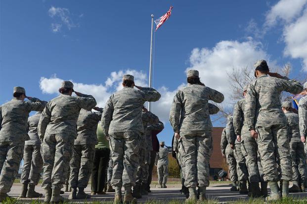 Airmen salute the American flag as it is lowered during the women’s retreat ceremony at Ellsworth Air Force Base, S.D., April 7, 2016. (U.S. Air Force/Airman Donald C. Knechtel/Released)