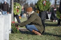 A volunteer place wreaths at a headstone in Section 60 during the Wreaths Across America event at Arlington National Cemetery, Arlington, Virginia, Dec. 16, 2017. (U.S. Army/Elizabeth Faser).