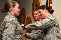 U.S. Air Force Lt. Col. Scott Cline, 312th Training Squadron commander, watches as Airman 1st Class Erin Prosser pins a duty badge onto Airman Emma Prosser at her graduation from the Louis F. Garland Department of Defense Fire Academy on Goodfellow Air Force Base, Texas, Dec. 3, 2018. Erin and Emma Prosser are twins, Erin joined the Air Force shortly before her sister and graduated the fire academy in March of 2018. (U.S. Air Force photo/Seraiah Hines)