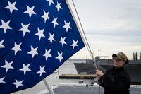 Quartermaster 2nd Class Taylor Miller, from Kent, Ohio, unfurls the union jack on the jack staff of the aircraft carrier USS Dwight D. Eisenhower (CVN 69). Dwight D. Eisenhower is undergoing a planned incremental availability during the maintenance phase of the Optimized Fleet  Response Plan. (Kaleb Sarten/Navy)