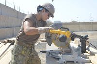 Construction electrician constructionman Stephanie N. Bugaski, from Naval Mobile Construction Battalion 133, deployed with the Combined Joint Task Force – Horn of Africa, cuts wood for new bus stops onboard Camp Lemonnier.
