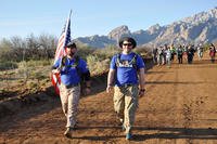 Bret Baker (left) of Albuquerque NM, and Alexander Stelly (right) from Miami FL tackle the march flag in hand. The two are marching in support of the Wounded Warrior Project, March 17, 2019. (U.S. Army photo/Caleb Creech)