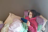 girl sitting on bed looking at kindle