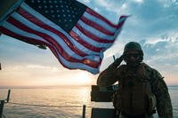 service member saluting flag in the background