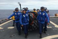 The crew of the Coast Guard Cutter Kimball moves simulated supplies.