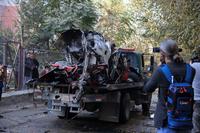 Afghans check car destroyed by an attached bomb in Kabul, Afghanistan.