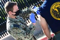 Hospital Corpsman gives a COVID-19 vaccine to a sailor.