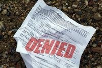 Crumpled paper loan application with red stamp reading "Denied"