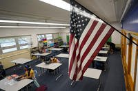 An American flag is in a classroom as students work on laptops