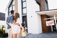 Family Gazing at New Home with Sold Sign