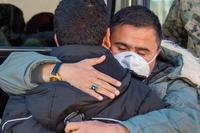 Afghan evacuees embrace before they board a bus and depart