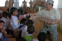 A Hawaii National Guardsman distributes milk to children in Thailand.