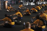 Chief petty officers and chief petty officer selects stretch after a workout.