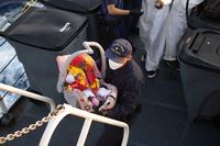 Coast Guard Cutter Thetis crew member brings Haitian infant up the stairs of the ship.