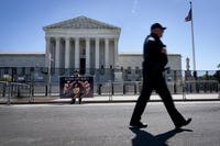 A Colorado man holds a sign saying &quot;hands off Roe&quot; as a Capitol police officer walks past barricades outside of the Supreme Court.