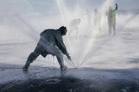 Airman David Kramer adjusts an aqueous film-forming foam sprinkler on the flight deck of amphibious assault ship USS Makin Island.