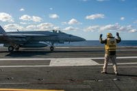 Ensign Terrance Wever signals to an F/A-18E Super Hornet on the flight deck of the U.S. Navy’s only forward-deployed aircraft carrier, USS Ronald Reagan.