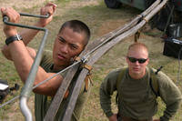 Pfc. Saree Ath moves the TRC-170 dish while Cpl. Robert E. Harvey supervises at Kin Blue Beach in Okinawa, Japan.