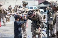 A Marine and a Afghan child spray water at each other during an evacuation.