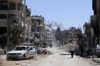Syrians walk through destruction in the town of Douma